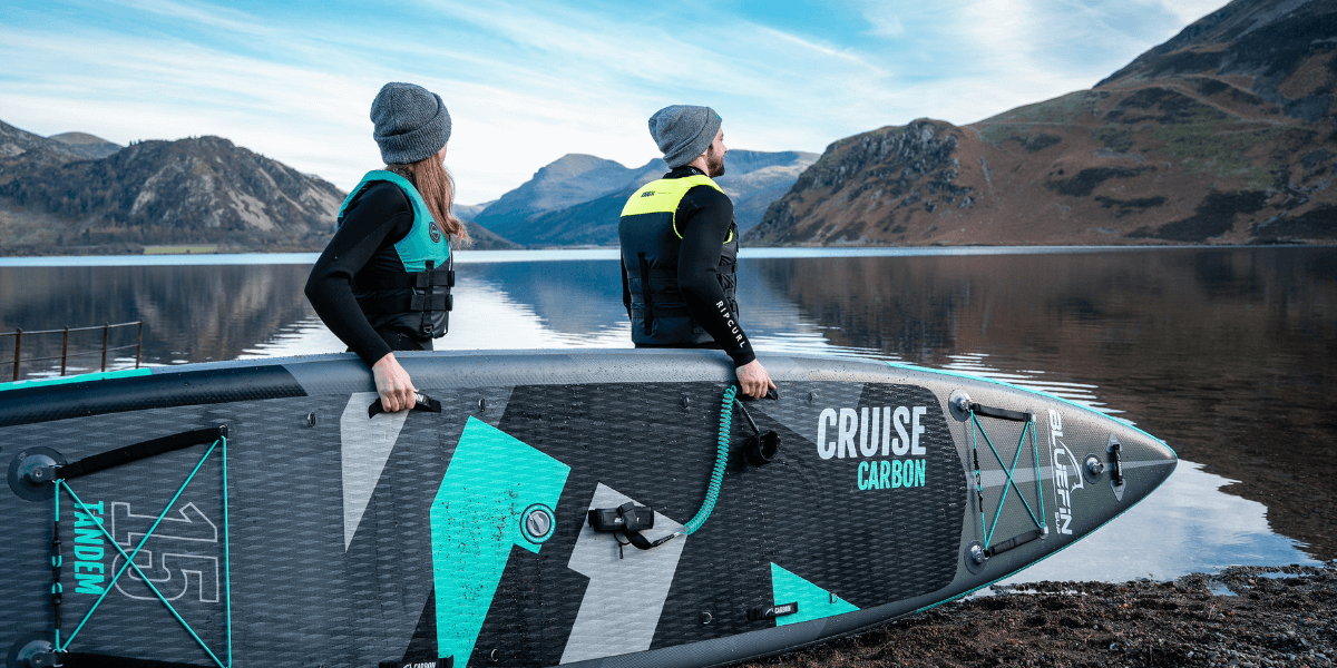 Two people about to go into a lake on a Bluefin SUP