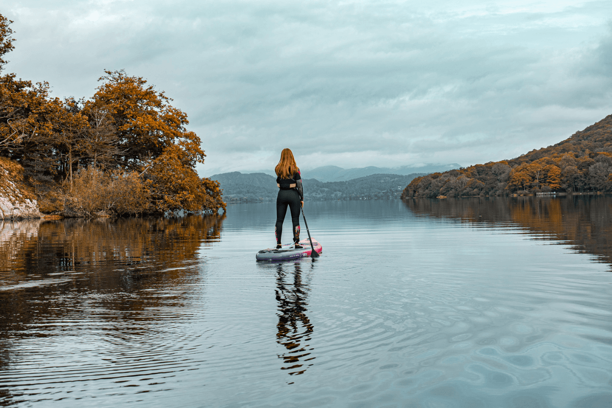 woman paddleboarding on an autumnal lake