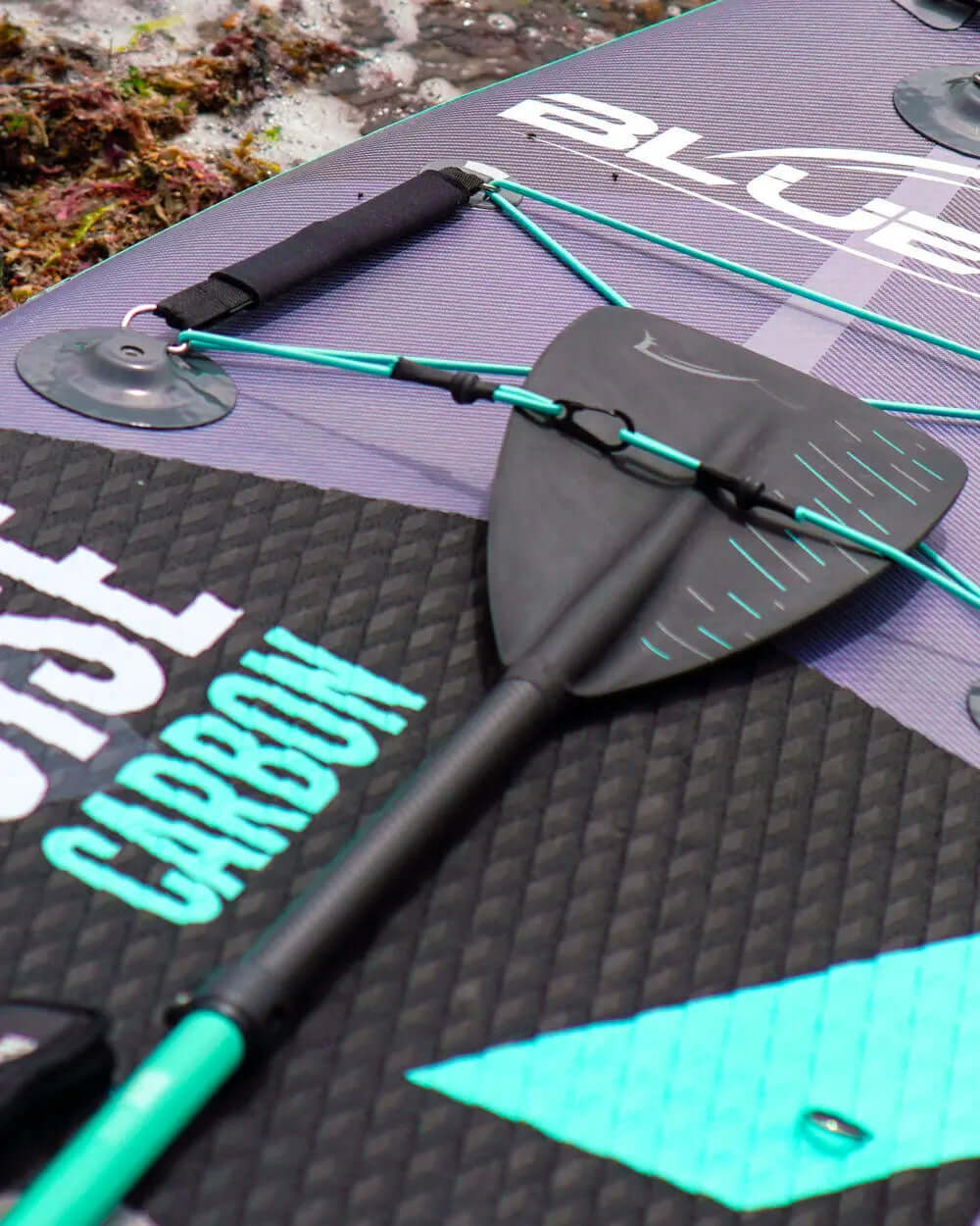 Inflatable paddleboard with carbon paddle, textured deck, and suction cups for securing gear