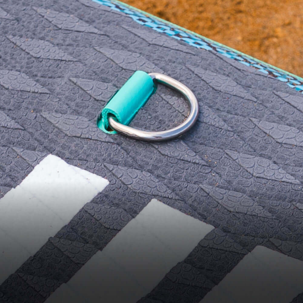 Close-up of a textured paddleboard surface with a metal D-ring and turquoise attachment loop