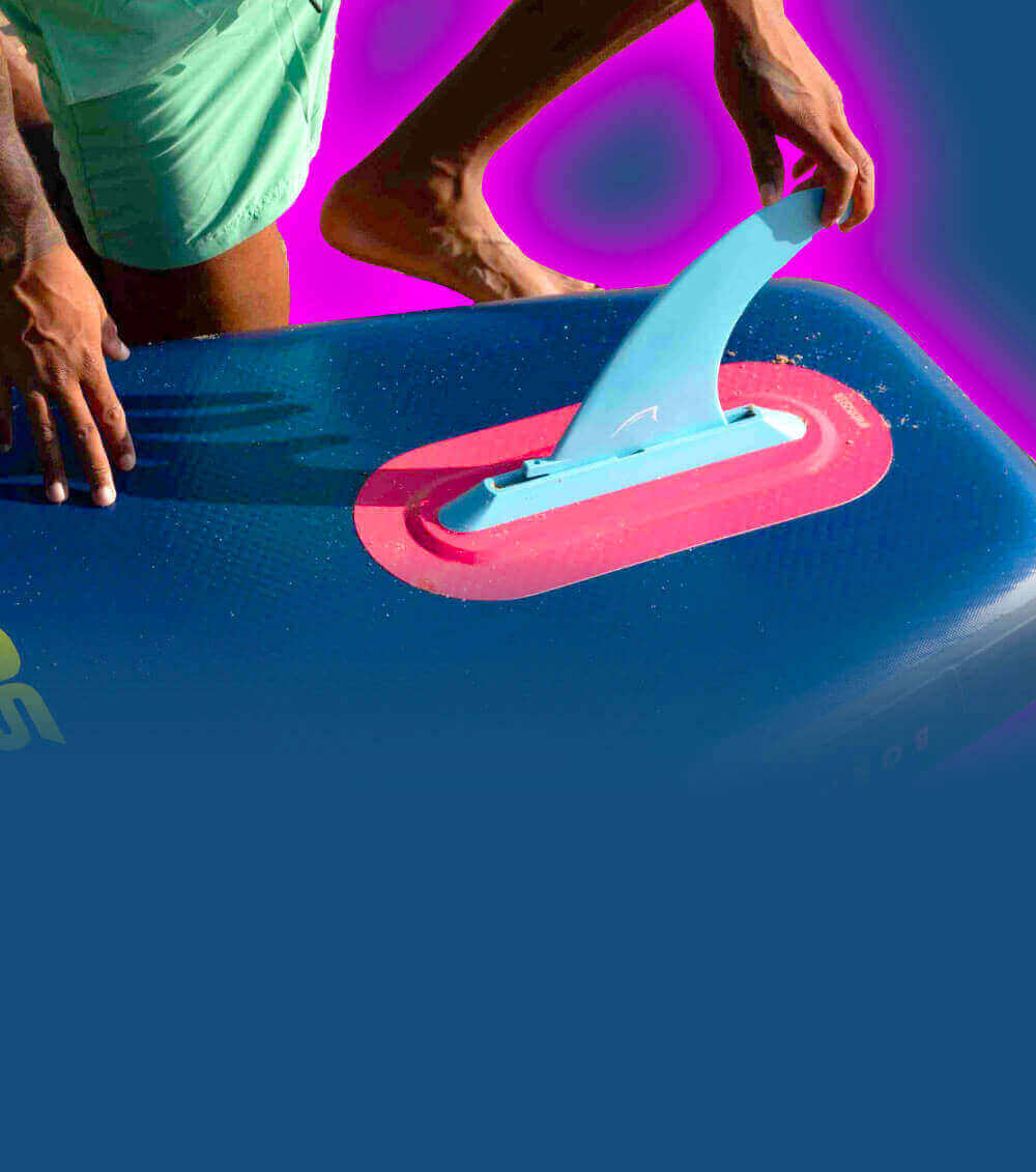 Person attaching a blue fin to a paddleboard with a textured surface and red base
