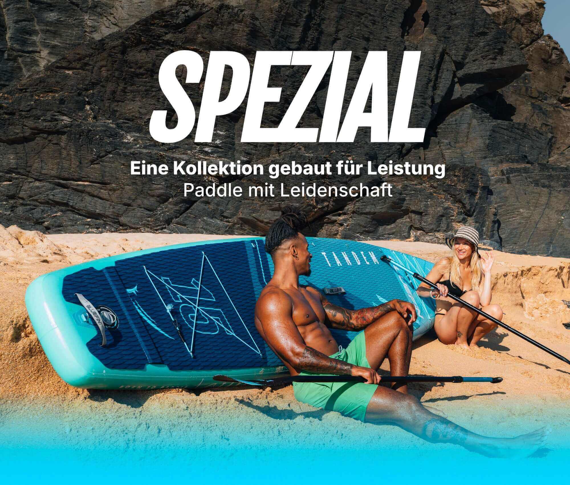 Two people on a beach with an inflatable paddleboard, one sitting and one kneeling, both holding paddles.