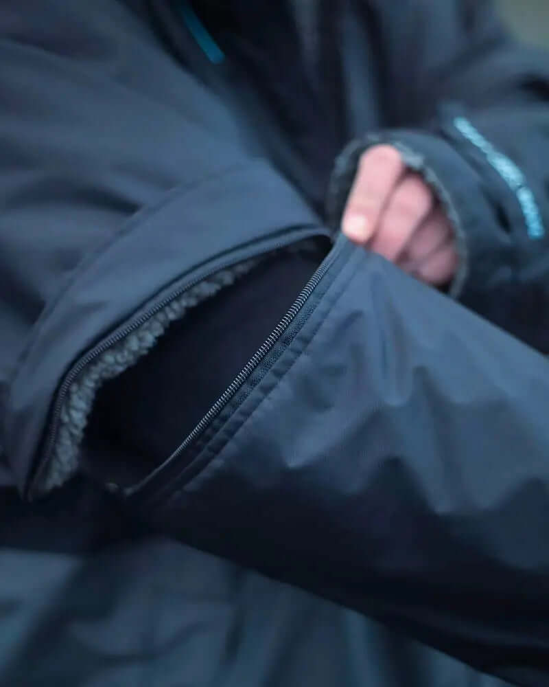Close-up of a black jacket sleeve with a zippered pocket and fleece lining visible.