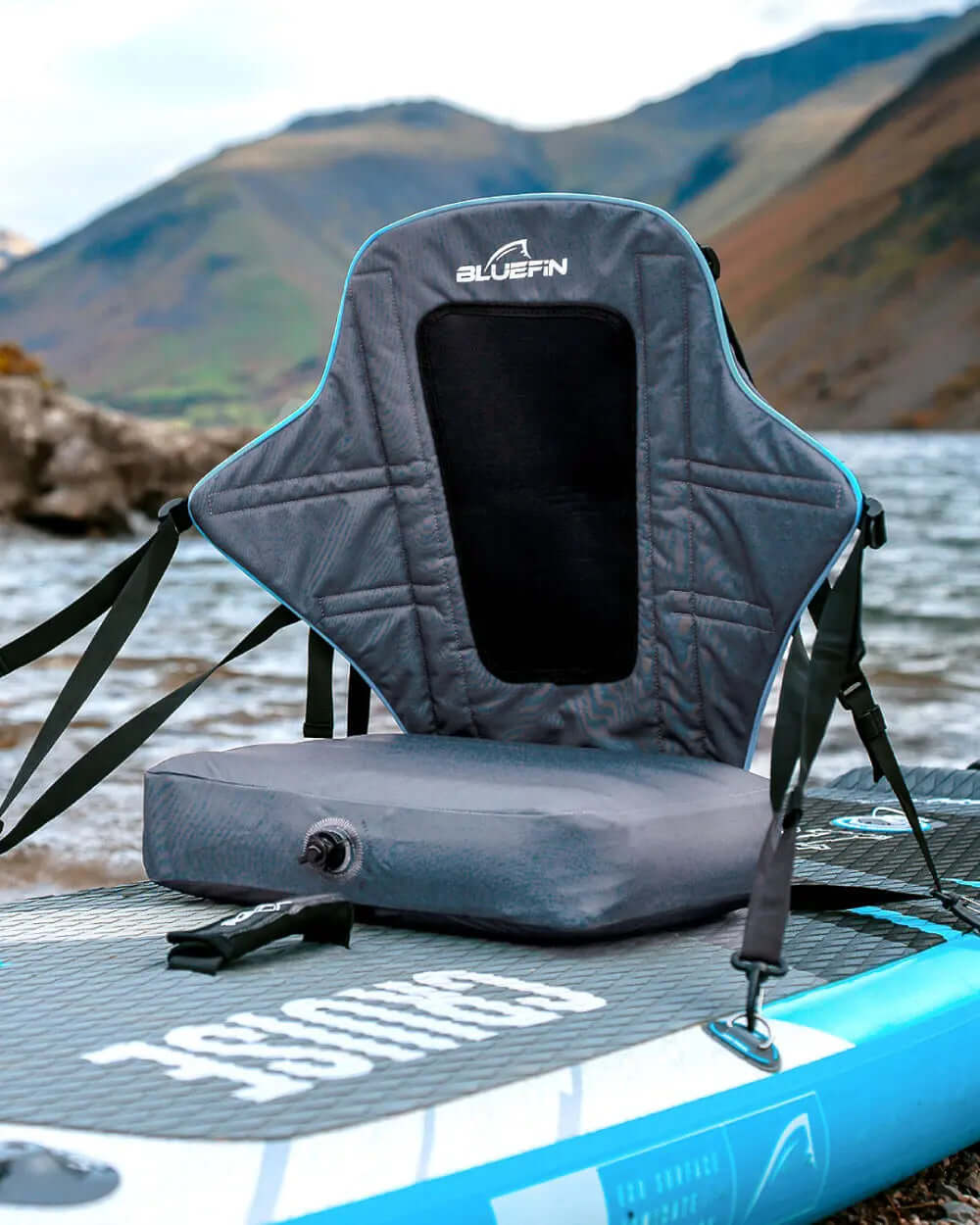 Bluefin SUP seat with backrest, straps, and inflation valve on a paddleboard by the water