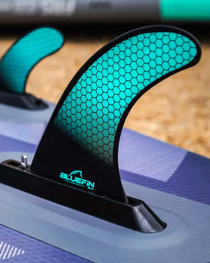 Nahaufnahme einer Paddleboard-Flosse mit Wabenmuster und BLUEFIN-Logo auf einer strukturierten Oberfläche