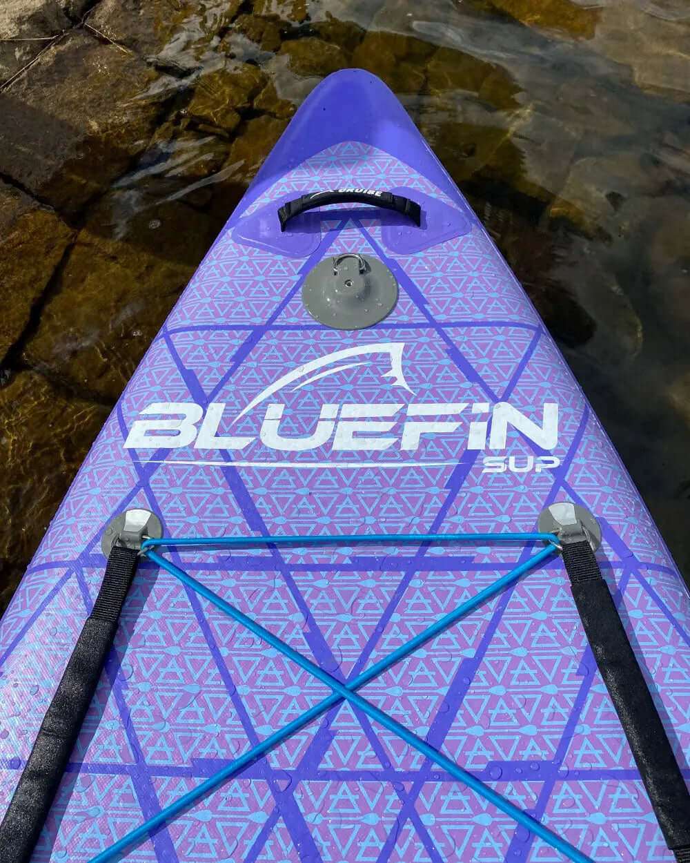 Inflatable paddleboard with purple geometric design, center fin, and bungee cord for gear storage
