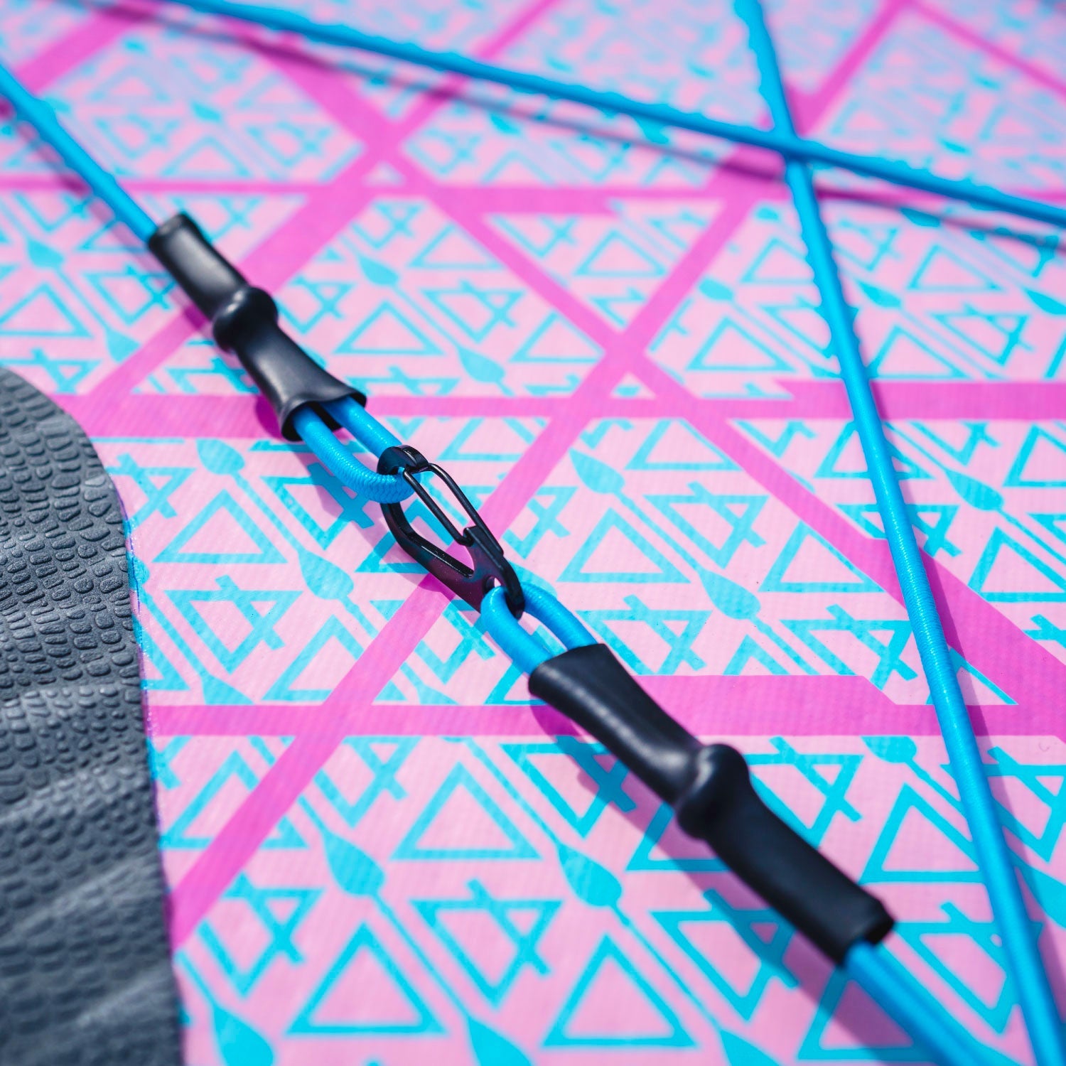 Close-up of blue straps and clips on a pink patterned inflatable paddleboard surface
