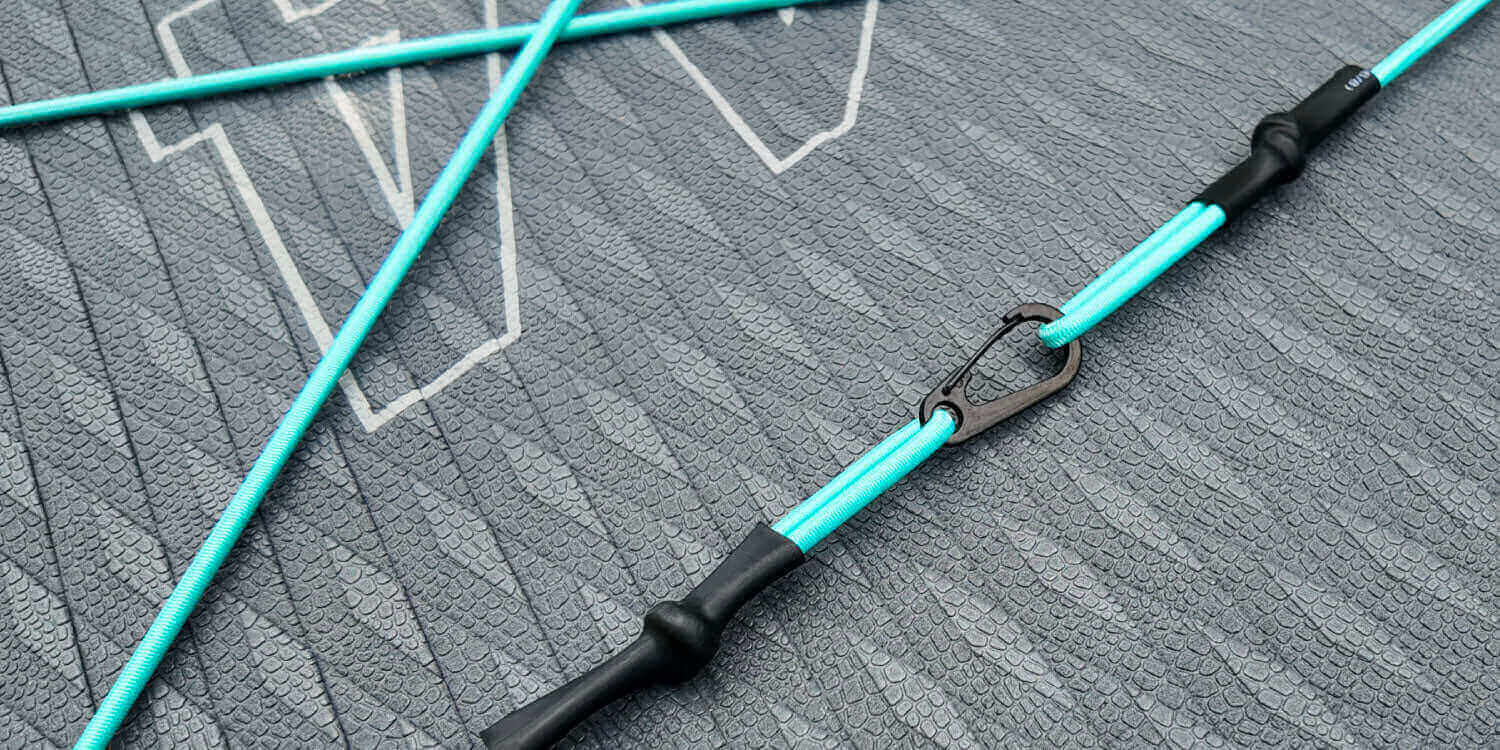 Close-up of a turquoise paddleboard leash with a black clip on a textured gray surface