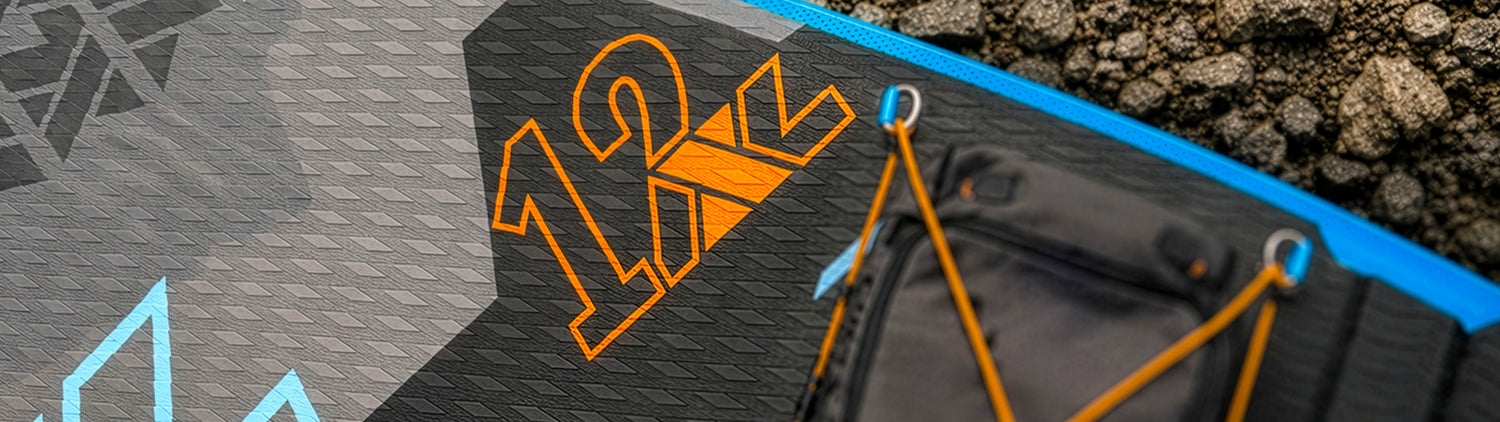 Close-up of inflatable paddleboard deck showing textured surface, orange 12' logo, and black storage area.
