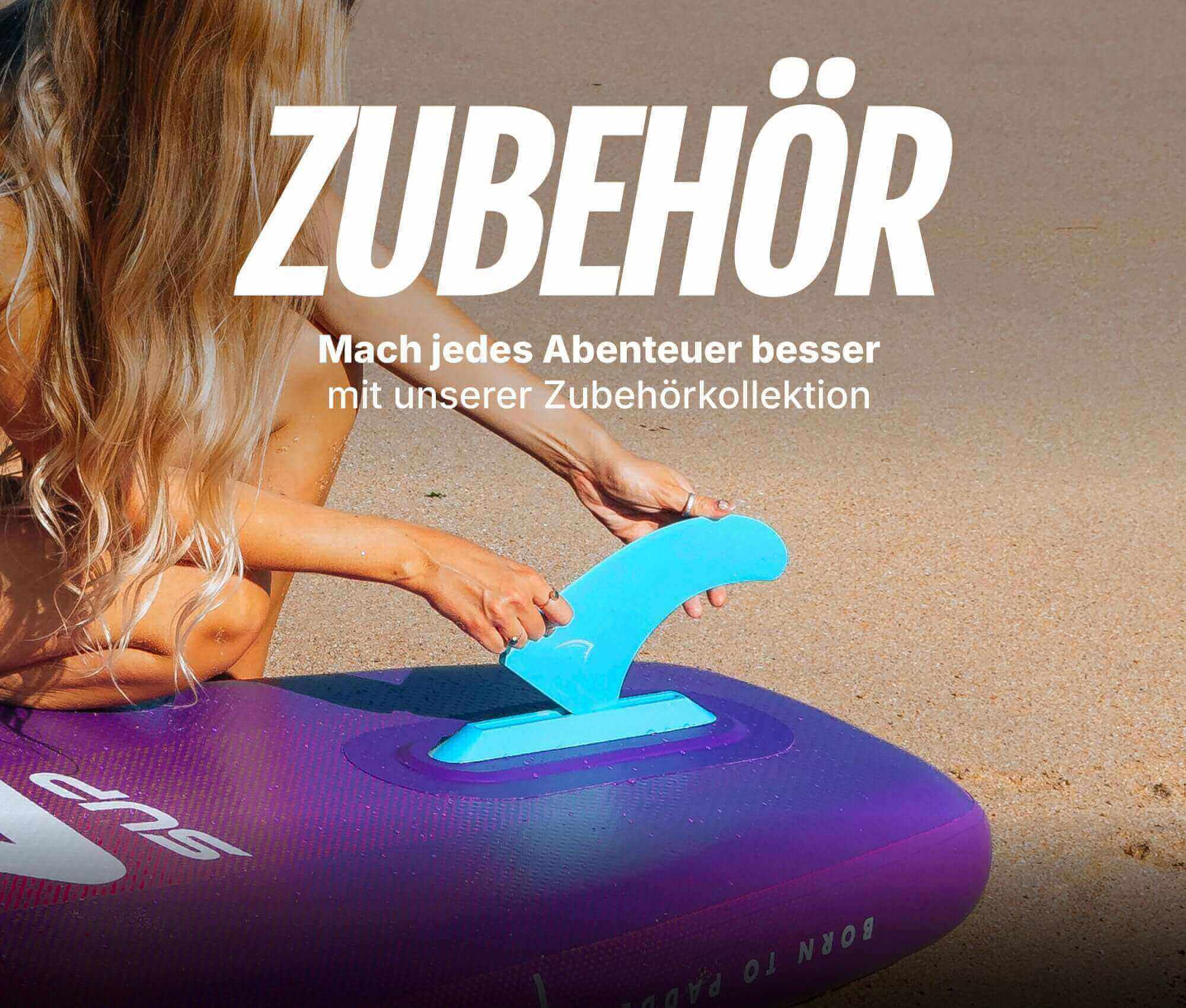 Person attaching a blue fin to a purple inflatable paddleboard on a sandy beach