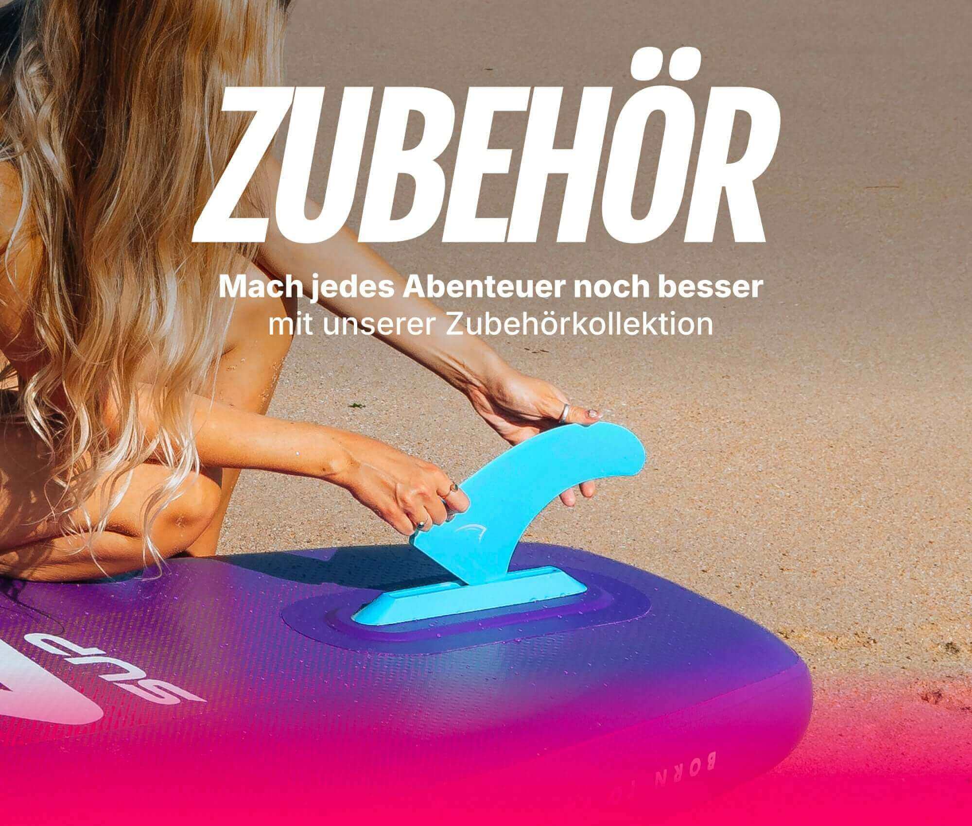 Person attaching a blue fin to a purple inflatable paddleboard on a sandy beach