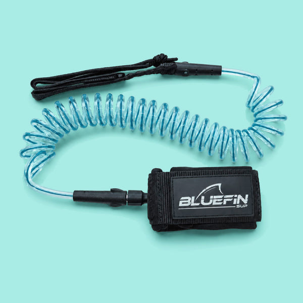 Coiled blue safety leash with black wrist strap and BLUEFIN SUP logo on the attachment.