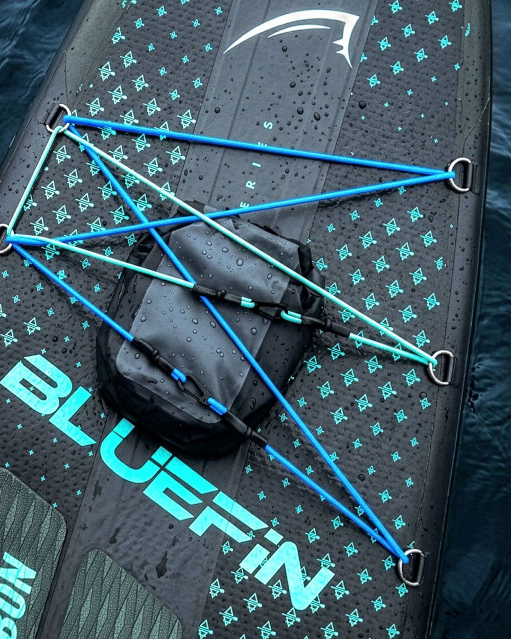 Inflatable paddleboard with blue bungee cords, textured surface, and a waterproof storage bag