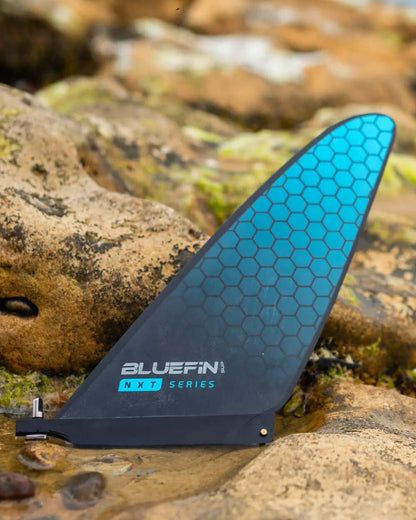 Bluefin NXT Series fin with a hexagonal pattern, resting on rocky terrain near water.